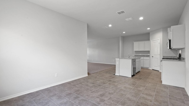 kitchen with light stone counters, an island with sink, recessed lighting, and visible vents