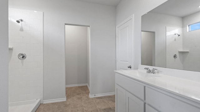 full bathroom with vanity, baseboards, tile patterned flooring, and a tile shower