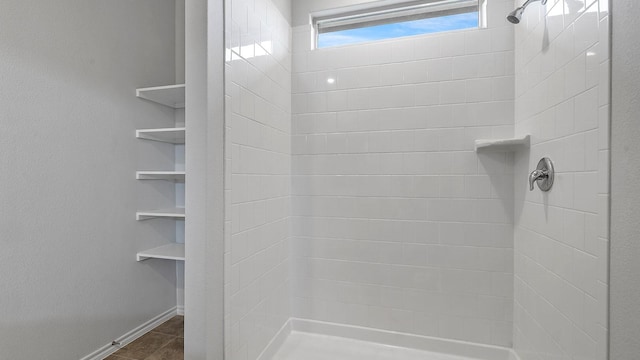 bathroom with baseboards and tiled shower
