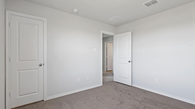 unfurnished bedroom featuring baseboards, carpet flooring, and visible vents