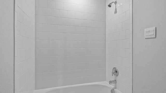 full bathroom with shower / tub combination and a textured wall