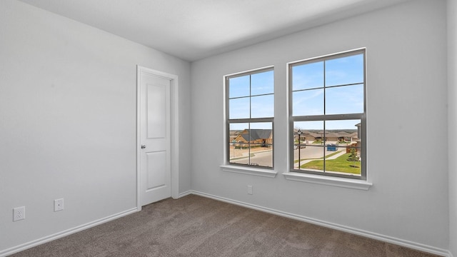 spare room featuring baseboards and dark colored carpet