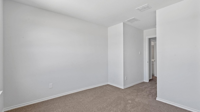 empty room with carpet floors, baseboards, and visible vents