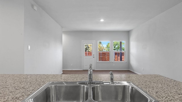 kitchen with baseboards, a sink, and carpet floors