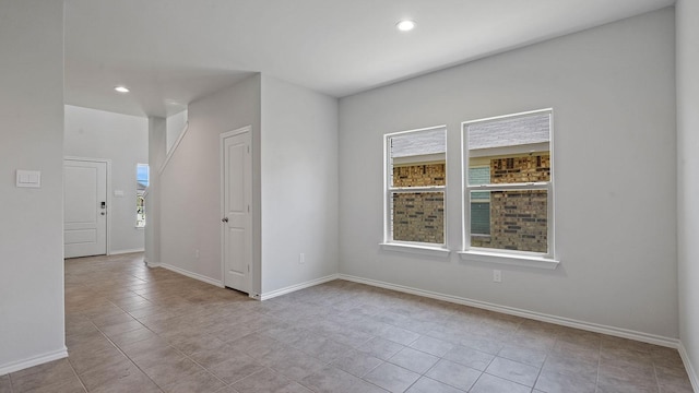tiled empty room featuring baseboards and recessed lighting