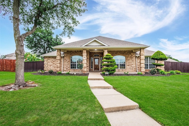 ranch-style house with brick siding, a shingled roof, a front lawn, and fence