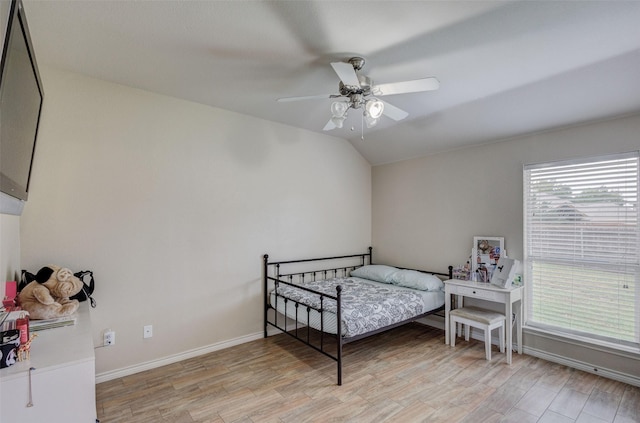 bedroom with baseboards, ceiling fan, light wood-style flooring, and lofted ceiling