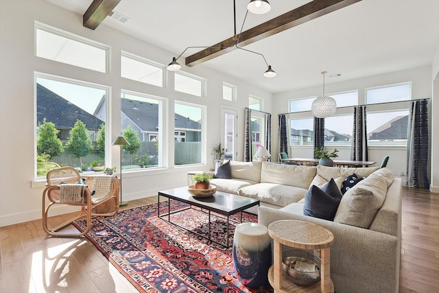 sunroom with a wealth of natural light, beamed ceiling, wood finished floors, and visible vents