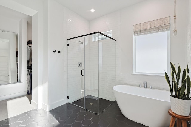 full bathroom featuring tile patterned flooring, a freestanding tub, recessed lighting, a spacious closet, and a shower stall