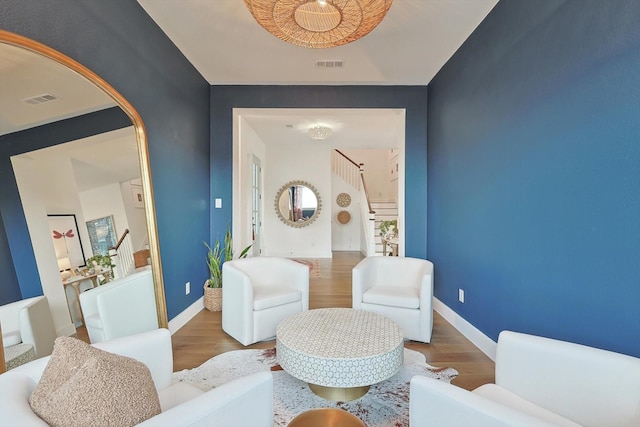 living area featuring baseboards, visible vents, and wood finished floors