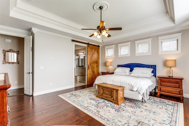 bedroom with crown molding, a tray ceiling, a barn door, and wood finished floors