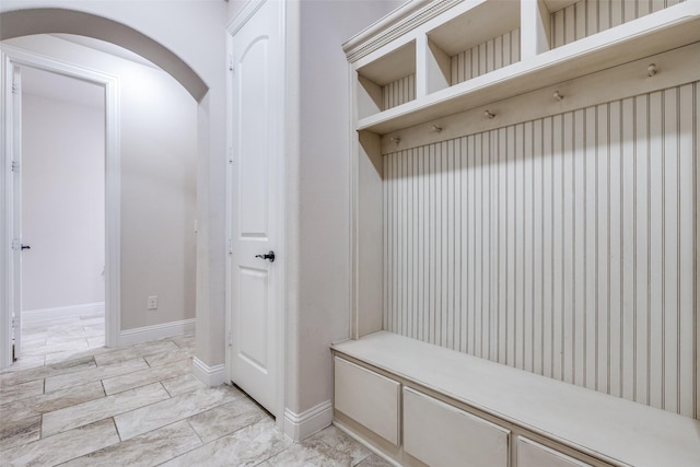 mudroom featuring arched walkways and baseboards
