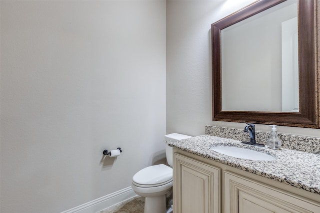 bathroom featuring baseboards, toilet, and vanity