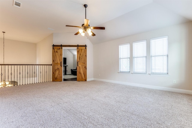 carpeted empty room with visible vents, lofted ceiling, baseboards, a barn door, and a ceiling fan