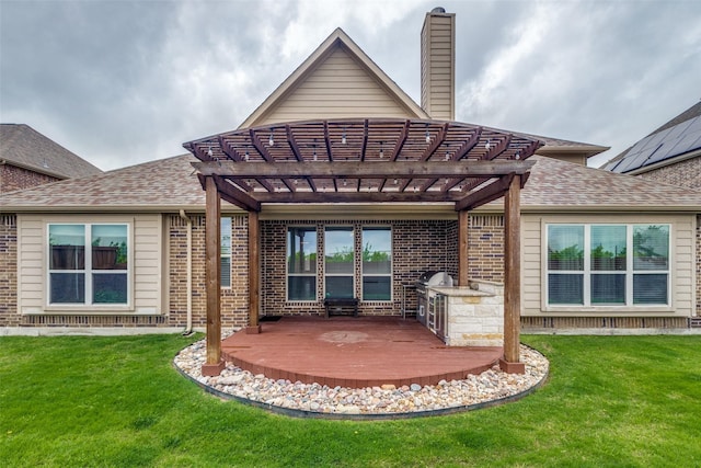 back of property featuring brick siding, a pergola, and a lawn