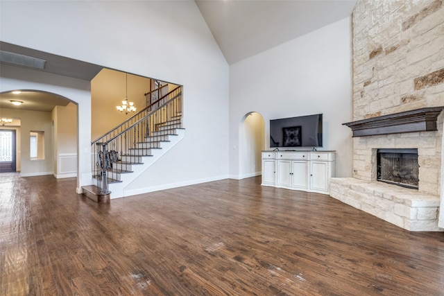 unfurnished living room featuring an inviting chandelier, high vaulted ceiling, stairway, and visible vents