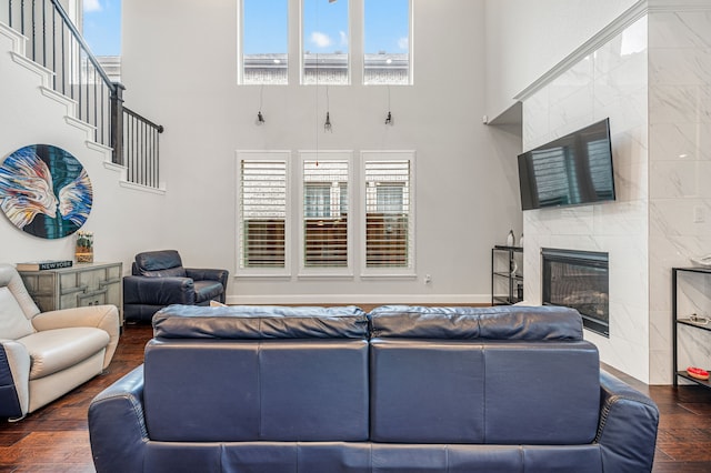 living room featuring a high ceiling, wood finished floors, a healthy amount of sunlight, and a fireplace