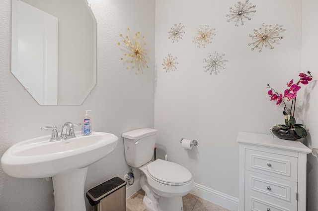 bathroom featuring a sink, baseboards, tile patterned flooring, and toilet