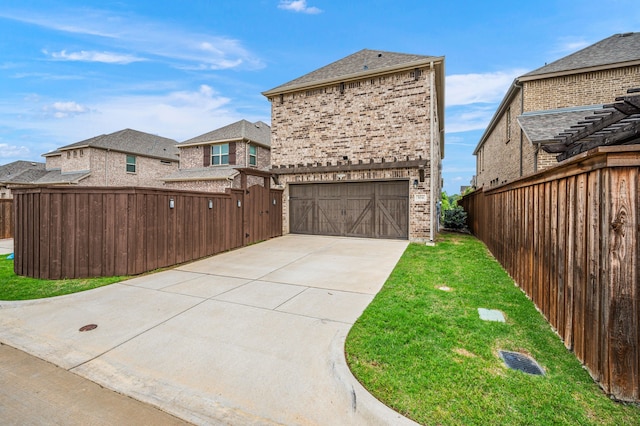back of property with fence, an attached garage, brick siding, a lawn, and driveway