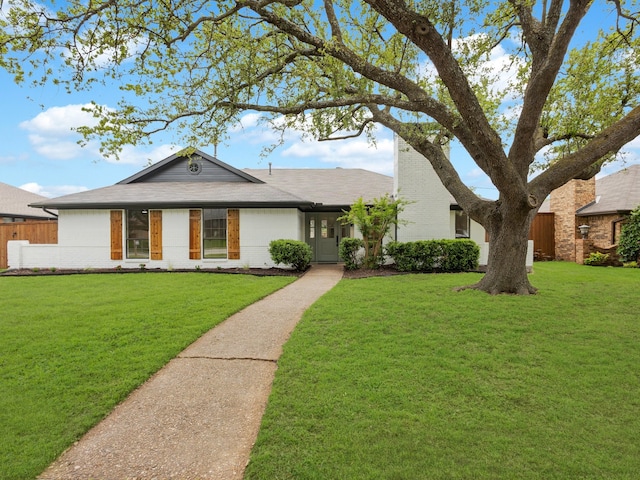 view of front of house featuring brick siding, fence, and a front yard