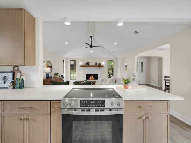 kitchen with ceiling fan, a brick fireplace, light wood-type flooring, stainless steel electric stove, and light brown cabinets