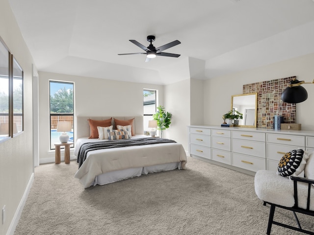 carpeted bedroom with a ceiling fan, baseboards, and a raised ceiling
