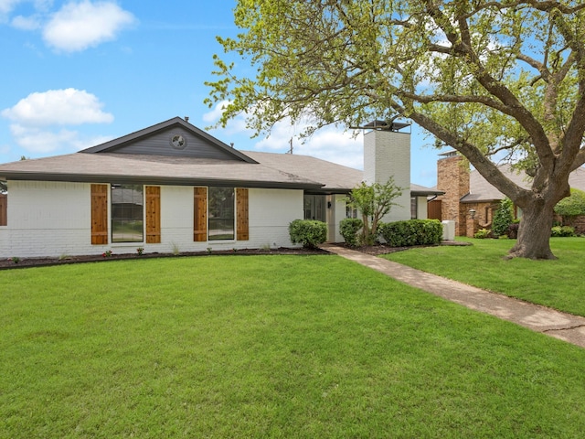 single story home featuring brick siding, a chimney, and a front lawn