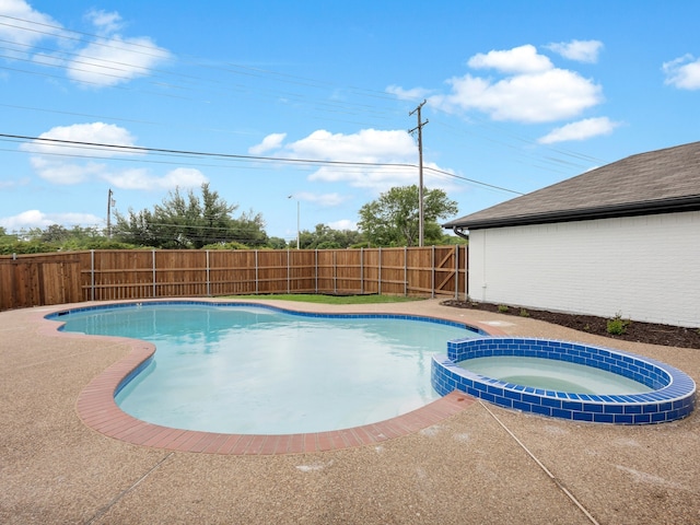view of pool with a fenced backyard and a pool with connected hot tub