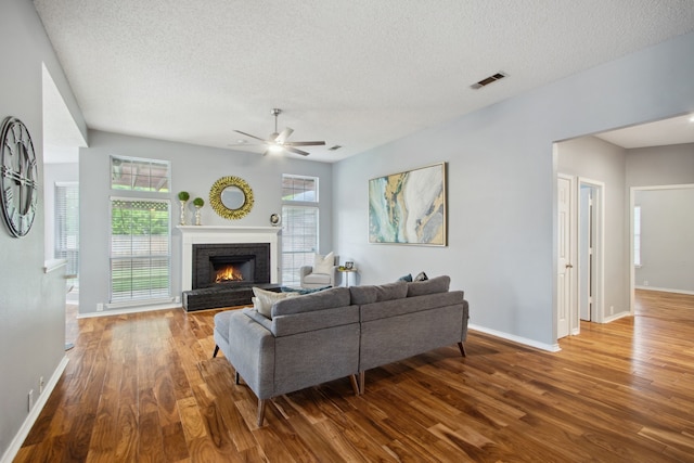 living room with visible vents, a ceiling fan, baseboards, and wood finished floors