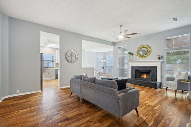 living area featuring a textured ceiling, ceiling fan, visible vents, and wood finished floors
