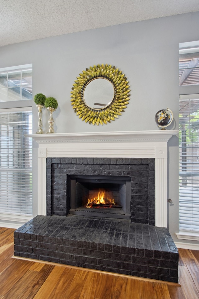 interior details with a textured ceiling, wood finished floors, and a fireplace