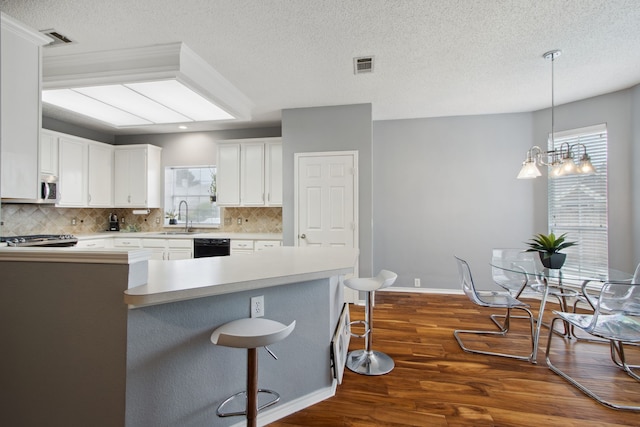 kitchen featuring visible vents, a sink, decorative backsplash, and a kitchen bar