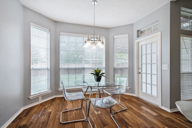 dining space featuring an inviting chandelier, baseboards, a textured ceiling, and wood finished floors