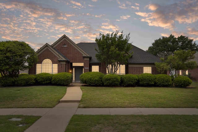 view of front facade with brick siding and a front lawn