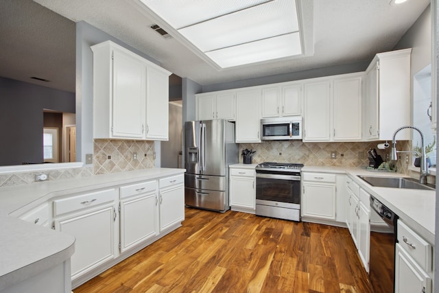 kitchen featuring white cabinets, appliances with stainless steel finishes, a sink, light wood-style floors, and light countertops