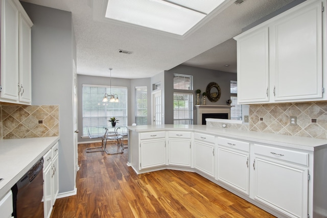 kitchen featuring dishwasher, light countertops, white cabinets, a chandelier, and light wood-style floors