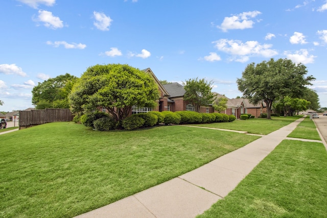 exterior space with fence, a yard, and brick siding