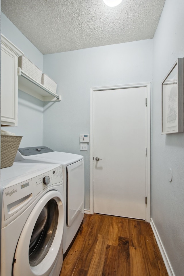 laundry area with washer and dryer, a textured ceiling, baseboards, and wood finished floors