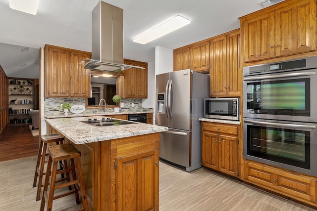 4705 El Salvador Ct, Arlington, TX 76017 - kitchen with appliances with stainless steel finishes, tasteful backsplash, brown cabinetry, and island range hood