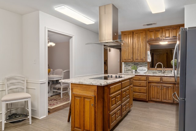 4705 El Salvador Ct, Arlington, TX 76017 - kitchen with brown cabinetry, backsplash, island range hood, freestanding refrigerator, and black electric stovetop