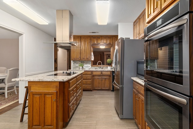 4705 El Salvador Ct, Arlington, TX 76017 - kitchen with island exhaust hood, visible vents, appliances with stainless steel finishes, tasteful backsplash, and brown cabinets