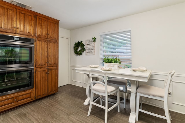 4705 El Salvador Ct, Arlington, TX 76017 - kitchen featuring visible vents, stainless steel double oven, brown cabinetry, and wainscoting