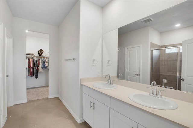 bathroom featuring double vanity, a sink, a stall shower, and a spacious closet