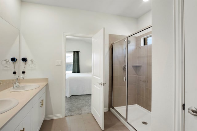 bathroom featuring tile patterned flooring, a shower stall, a sink, baseboards, and ensuite bathroom