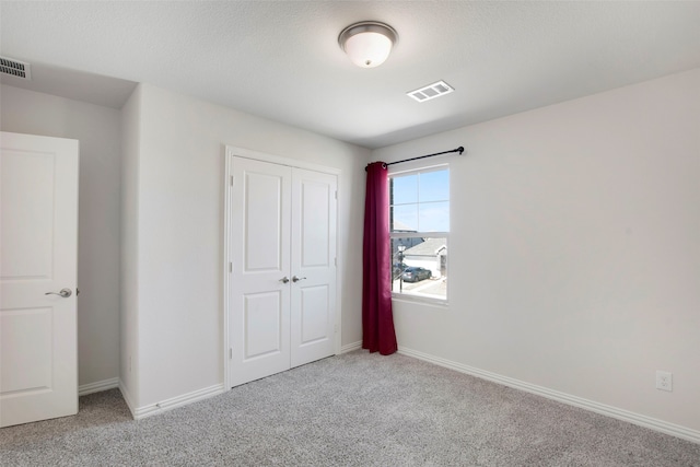 unfurnished bedroom featuring carpet floors, visible vents, and a closet