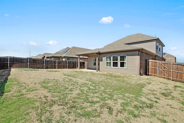 rear view of property featuring a fenced backyard, a lawn, and brick siding