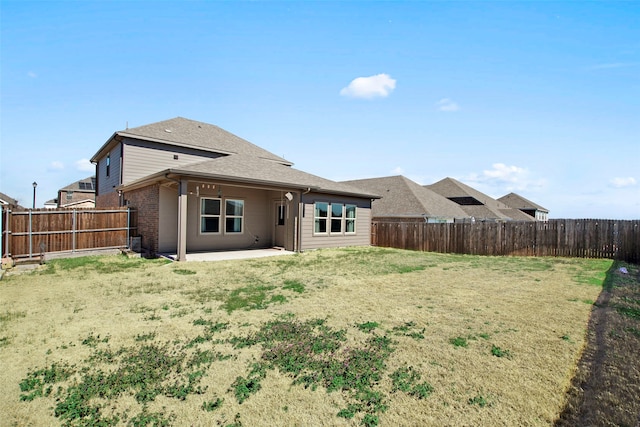 rear view of property with a patio, a fenced backyard, a yard, and brick siding