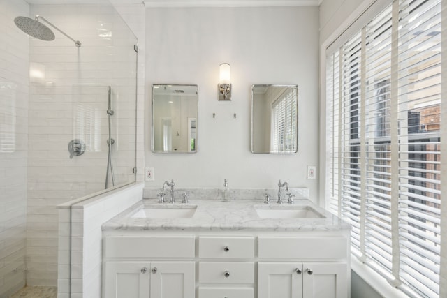 full bathroom with double vanity, a sink, and tiled shower