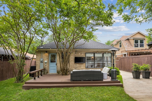 rear view of house with fence, roof with shingles, and a deck