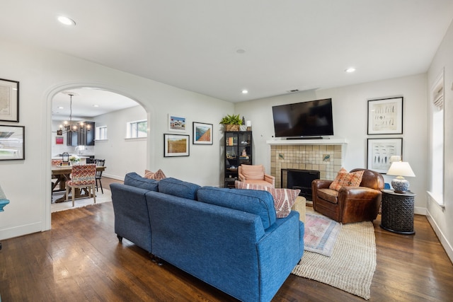 living room featuring recessed lighting, arched walkways, dark wood-style flooring, and a tile fireplace